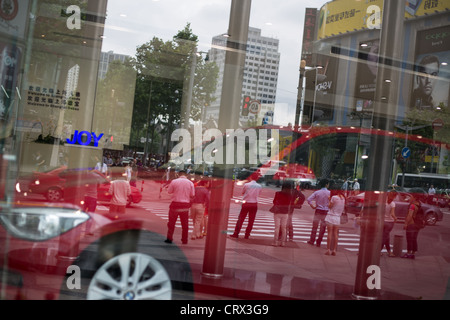 Les consommateurs et les piétons reflétée dans l'agence de voiture, à Shanghai, en Chine. Banque D'Images