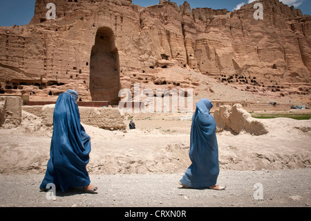 Deux femmes passent devant l'énorme cavité où l'un des anciens Bouddhas de Bamiyan, appellent les gens comme le 'Père' Bouddha, utilisé pour se tenir, le 17 juin 2012 à Bamiyan, en Afghanistan. Les statues monumentales ont été construits en l'an 507 et 554 et ont été la plus grande des statues de Bouddha debout sur la terre jusqu'à ce que les talibans ont détruit en 2001. Banque D'Images