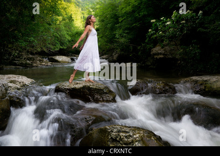 Belle jeune fille sur une rivière dans la forêt elle-même charge avec les énergies de la Nature Banque D'Images