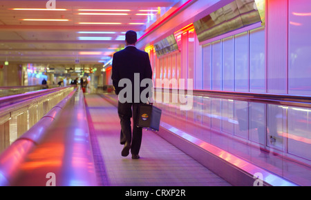 Un homme dans un couloir de Muenchen airport sur un escalator Banque D'Images