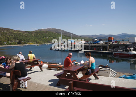 Ullapool Ross et Cromarty Ecosse peut touristes assis à des tables de pique-nique de manger du poisson et frites à l'Harbour Ville Loch Broom Banque D'Images