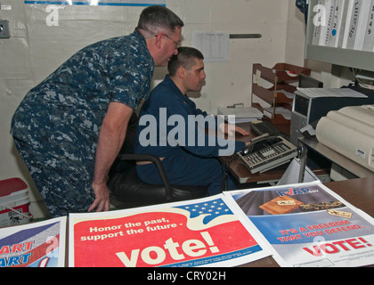 Le chef du service électronique de l'aviation, Greg Overhalser, à gauche, aide le chef du service hospitalier, Wayne Gonsorcik à s'inscrire pour voter pendant la semaine des électeurs des Forces armées et des citoyens d'outre-mer à bord du navire d'assaut amphibie polyvalent USS Iwo Jima (LHD 7). Iwo Jima et la 24e unité expéditionnaire maritime sont déployées à l'appui des opérations de sécurité maritime et des efforts de coopération en matière de sécurité de théâtre dans le domaine de responsabilité de la 5e flotte américaine. Banque D'Images