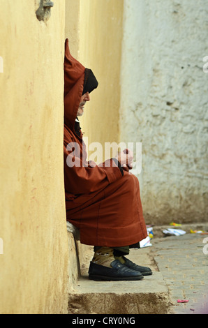 Un homme âgé assis dans une porte à Fes medina, Maroc Banque D'Images