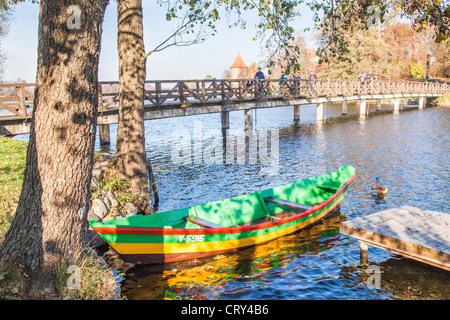 Un bateau à rames colorés amarrés sur lac Galve, Trakai, Lituanie par une passerelle en bois menant au château de Trakai Banque D'Images