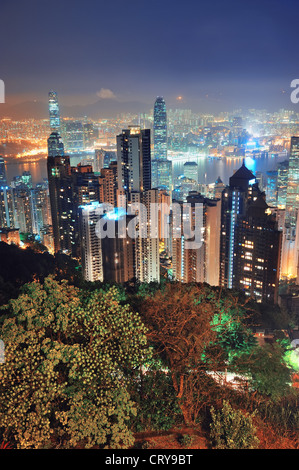 Hong Kong city skyline at night avec Victoria Harbour et gratte-ciel illuminé par des lumières au-dessus de l'eau vu du sommet de la montagne. Banque D'Images