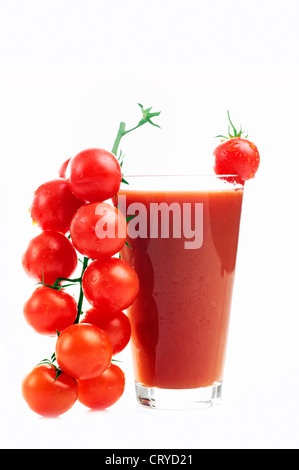 Dans un verre de jus de tomate et les tomates cerises. Isolé sur fond blanc Banque D'Images