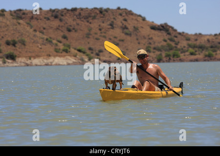 Jeune homme kayak avec un chien à l'avant du kayak Banque D'Images