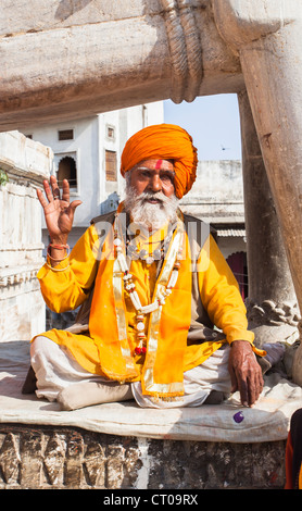 Indian Hindu Sadhu, saint homme, habillé en robe safran typique turban orange et donner une bénédiction à Jagdish Temple à Udaipur, Rajasthan, Inde Banque D'Images