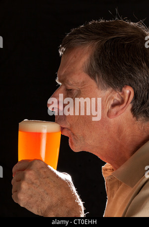 Young man in profile de boire une pinte de bière lager ou Banque D'Images