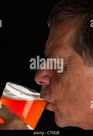 Young man in profile de boire une pinte de bière lager ou Banque D'Images
