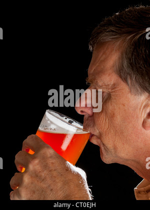 Young man in profile de boire une pinte de bière lager ou Banque D'Images