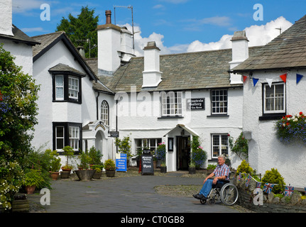 L'homme en fauteuil roulant dans le village de Hawkshead, Parc National de Lake District, Cumbria, Angleterre, Royaume-Uni Banque D'Images