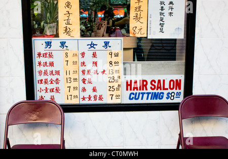Une liste de prix des services dans la fenêtre d'un salon de coiffure de Chinatown à New York City Banque D'Images