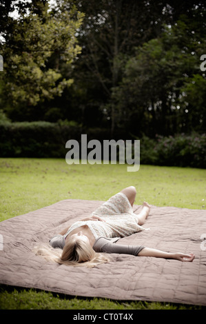 Woman laying on blanket in park Banque D'Images