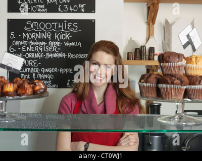 Server smiling derrière comptoir de boulangerie Banque D'Images