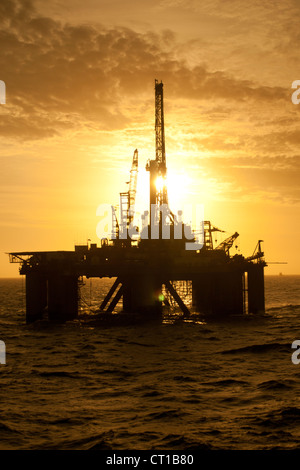 Silhouette d'offshore oil drilling rig au moment de coucher de soleil. Côte de l'état de Rio de Janeiro, le sud-est du Brésil. Banque D'Images