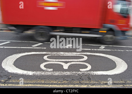 Signalisation indiquant une zone de 30 mph avec un royal mail van passant Banque D'Images