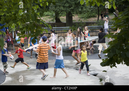 Enfants comme adultes se rafraîchir dans le domaine de l'eau d'une aire de jeux dans Prospect Park, Brooklyn, NY sur une chaude journée d'été. Banque D'Images