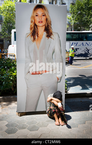 Femme mendiant sous un poster de Kate Moss Banque D'Images