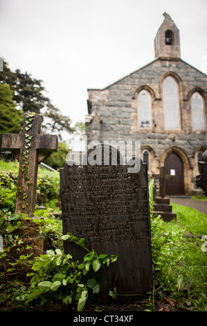 HARLECH, pays de Galles — Un chemin de gravier serpente à travers des pierres tombales altérées dans le cimetière de l'église de Tanwg à Harlech, sur la côte nord-ouest du pays de Galles. L'église historique, nichée dans la région de Snowdonia, se trouve au bout du chemin, ses murs de pierre témoignent de siècles d'héritage religieux gallois et de vie de village côtier. Banque D'Images