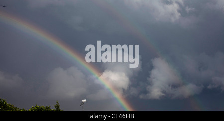 L'avion commence son travail décent dans l'aéroport Heathrow de Londres, comme les nuages de tempête et de masse d'un arc-en-ciel lumineux apparaît. Banque D'Images