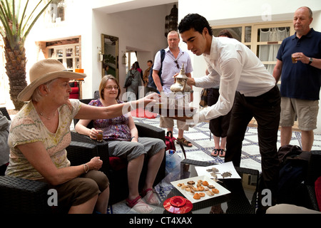 Les clients bénéficient d'un verre de bienvenue à partir d'un serveur dans l'accueil de la DAR L'Ouissa, Riad Essaouira Maroc Sud Banque D'Images