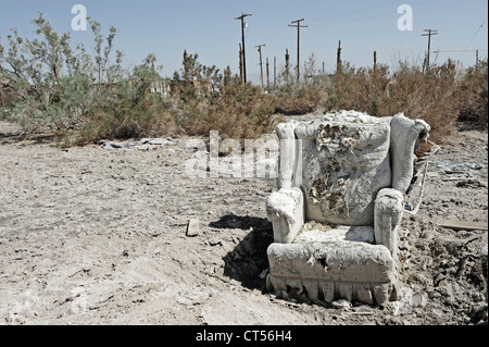 Une chaise abandonnée, Salton Sea Beach, Californie du Sud, USA. Fauteuil déchiré sur les broussailles, poteaux télégraphiques derrière. Banque D'Images