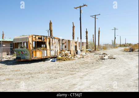 Remorque abandonnée sur la route, la mer de Salton, California, USA. Remorque couverte de graffiti, palmiers morts et des poteaux télégraphiques. Banque D'Images