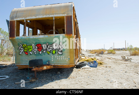 Remorque abandonnée sur la route, la mer de Salton, California, USA. Remorque couverte de graffiti, palmiers morts et des poteaux télégraphiques. Banque D'Images