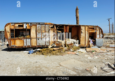 Remorque abandonnée sur la route, la mer de Salton, California, USA. Remorque couverte de graffiti, palmiers morts et des poteaux télégraphiques. Banque D'Images