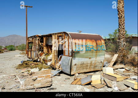 Remorque abandonnée sur la route, la mer de Salton, California, USA. Remorque couverte de graffiti, palmiers morts et des poteaux télégraphiques. Banque D'Images