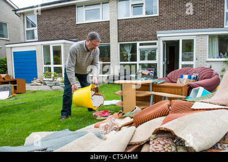 Un homme travaille la compensation des dommages causés à son domicile par les inondations au Royaume-Uni Aberystwyth Juin 2012 - dumping possessions en dehors de la pelouse house Banque D'Images