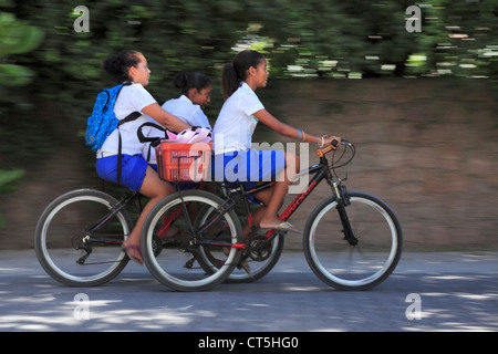 Trois jeunes filles faire du vélo à la maison de l'école sur l'île de La Digue aux Seychelles Banque D'Images