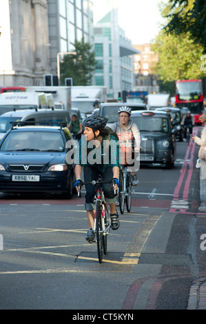 Les cyclistes équitation à travers le trafic important dans la ville de Londres, en Angleterre. Banque D'Images