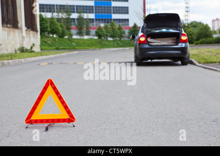 Triangle warning sign on road et d'avant-plan avec voiture cassée feux clignotant sur la route Banque D'Images