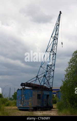 Une vieille Grue en décomposition, se trouve abandonné dans le port de Hambourg, Allemagne, sous un ciel de nuages de couvaison. Banque D'Images