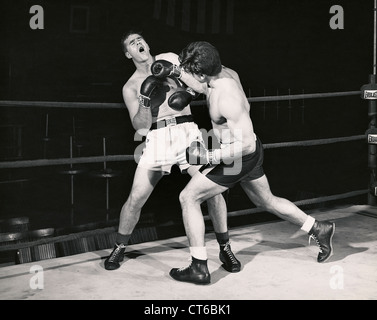 Boxer poinçons jette à l'adversaire contre les anneaux Banque D'Images