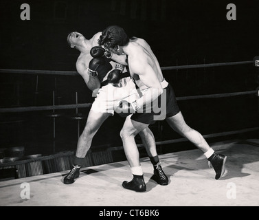 Boxer poinçons jette à l'adversaire contre les anneaux Banque D'Images