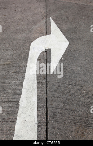 C'est une photo d'une flèche peinte sur la route pour indiquer la direction à suivre. Il est de couleur blanche et montre bonne direction Banque D'Images