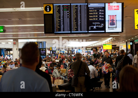 Les passagers des compagnies aériennes rechercher leurs vols de départ sur une carte électronique à Londres, en Angleterre, l'aéroport d'Heathrow à la borne 3. Banque D'Images