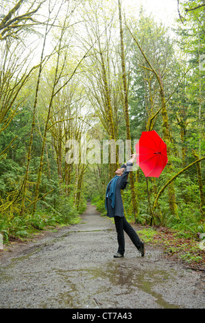 Femme sur chemin forestier avec parapluie rouge Banque D'Images