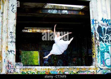 Ballerine faisant grand jete avec graffiti on wall Banque D'Images