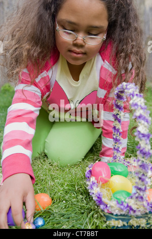 Girl trouver des oeufs de pâques dans l'herbe Banque D'Images