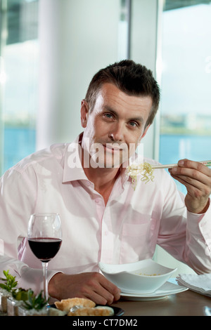 Businessman eating noodles, portrait Banque D'Images