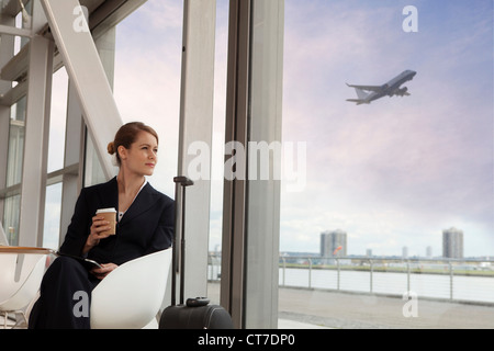 Businesswoman drinking coffee in airport Banque D'Images