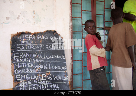 Pancarte mettant en valeur les jeux de football qui sont joués sur le village local de la télévision sur la soirée à venir à Migori, Kenya. Banque D'Images