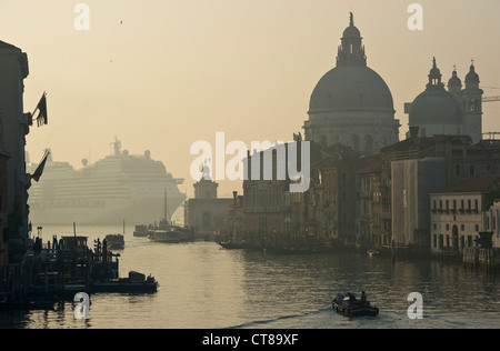 Un énorme bateau de croisière passe devant la basilique de Santa Maria della Salute à l'embouchure du Grand Canal à Venise, en Italie, tôt le matin Banque D'Images