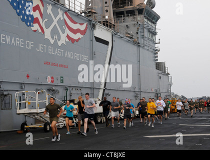 Les marins et les Marines affectés à la 24e unité expéditionnaire maritime (24e unité MEU) participent à une course de 5 kilomètres le jour de l'indépendance sur le pont de vol du navire d'assaut amphibie polyvalent USS Iwo Jima (LHD 7). Iwo Jima, le navire amiral du Iwo Jima Amphiobie Ready Group avec le 24e MEU embarqué, est déployé pour soutenir les opérations de sécurité maritime et les efforts de coopération en matière de sécurité de théâtre dans le domaine de responsabilité de la 5e flotte américaine. Banque D'Images