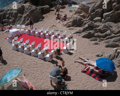 Chaises et tables avec un tapis rouge disposés sur une plage de sable fin pour une cérémonie de mariage entouré par les vacanciers Banque D'Images