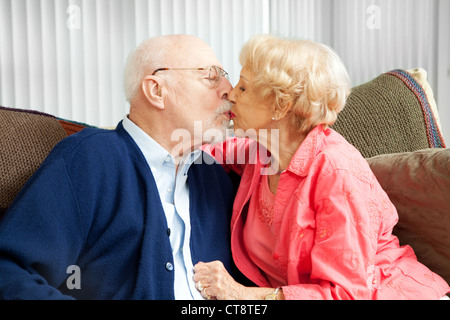 Senior couple in love, s'embrasser sur le canapé. Banque D'Images